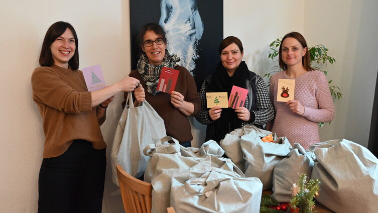 Pastorin Rebekka Tibbe (links) übergibt dem Team der Treppe 50 Weihnachtsbeutel mit von Konfis gestalteten Grußkarten / Foto Ahrens